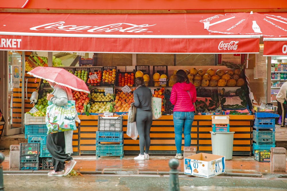 a group of people standing in front of a fruit stand