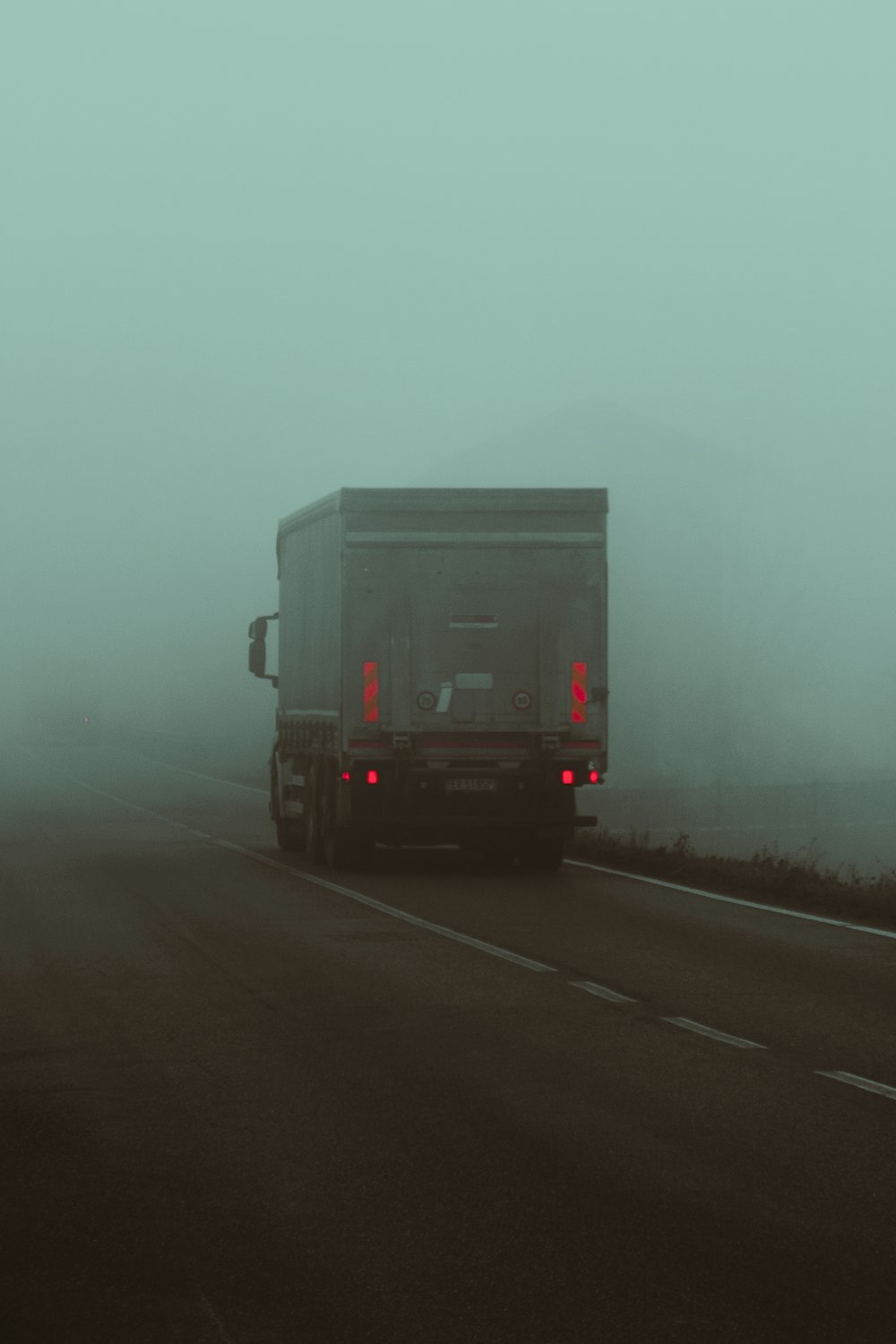 a semi truck driving down a foggy highway