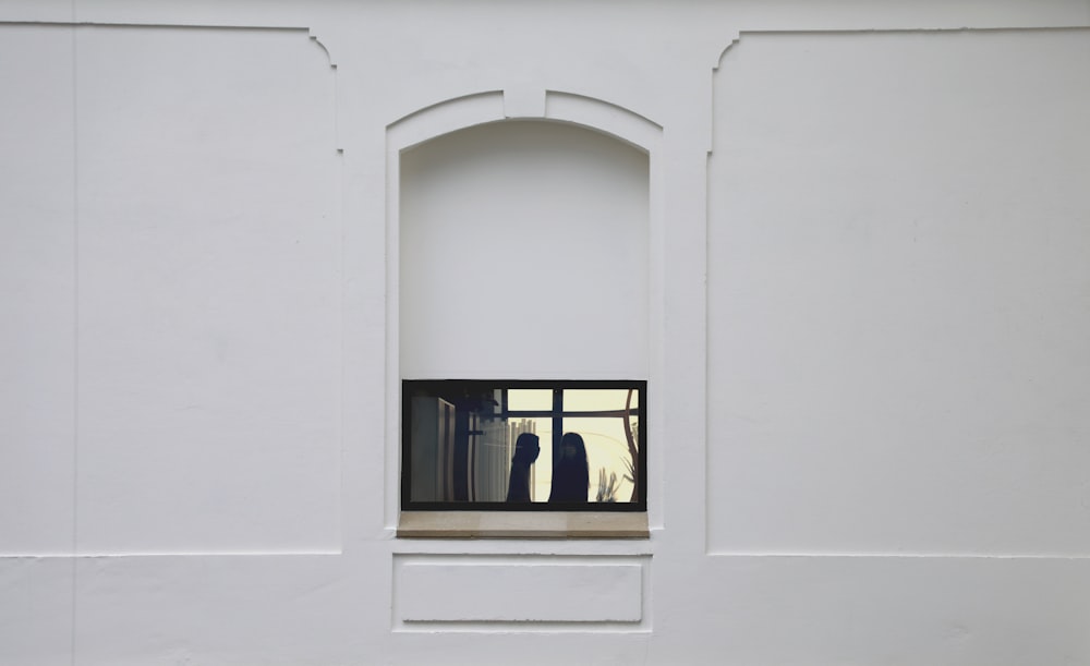 a white wall with a window and a vase in it