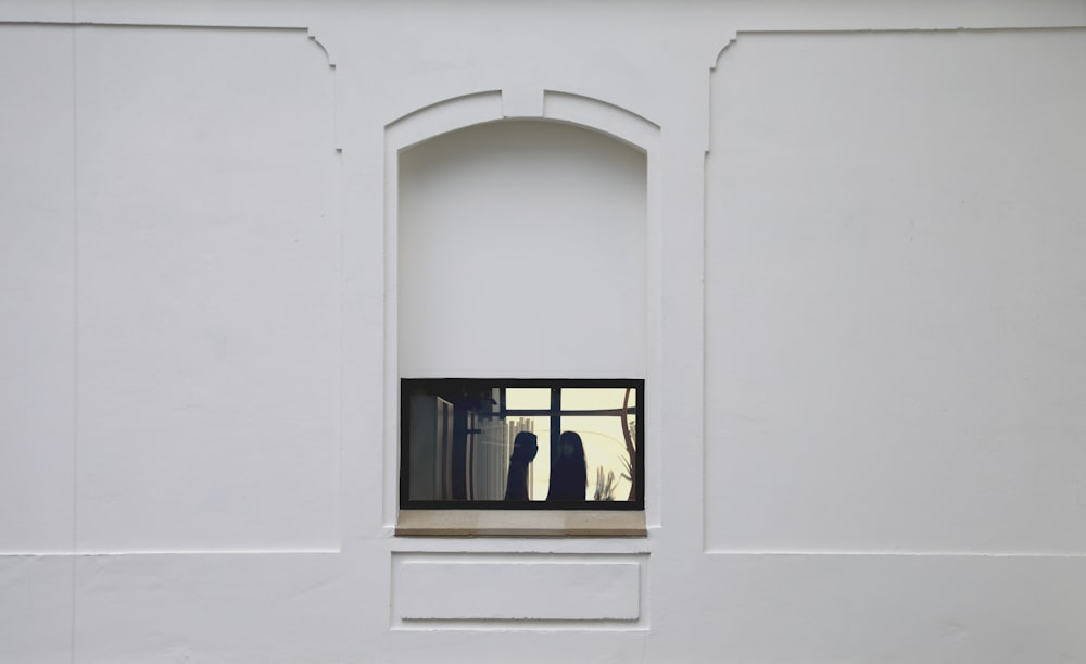 un muro bianco con una finestra e un vaso in esso