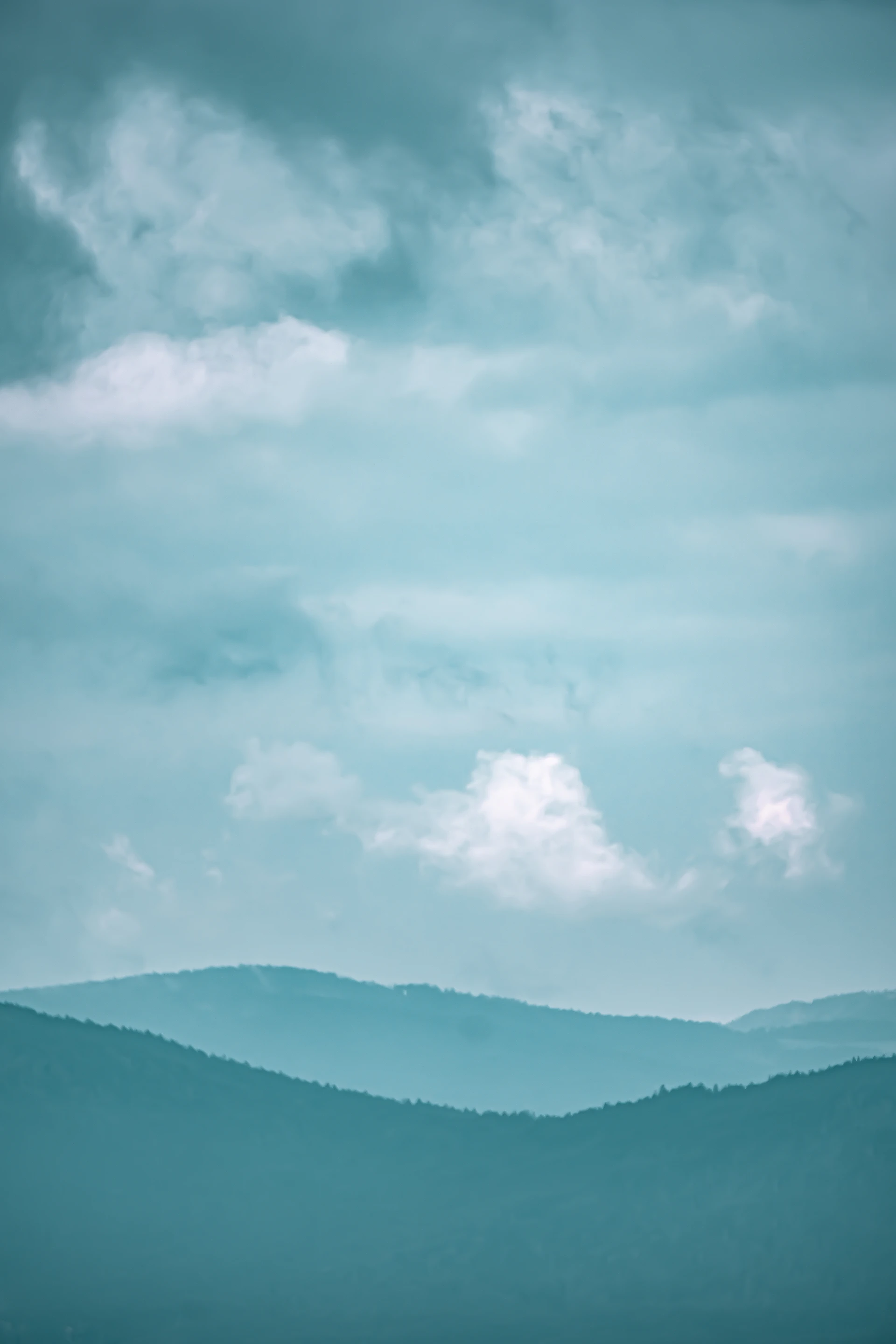 a plane flying over a mountain range under a cloudy sky