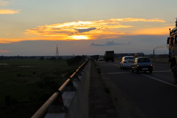 A car hauler truck loaded with vehicles driving on a highway at sunset.