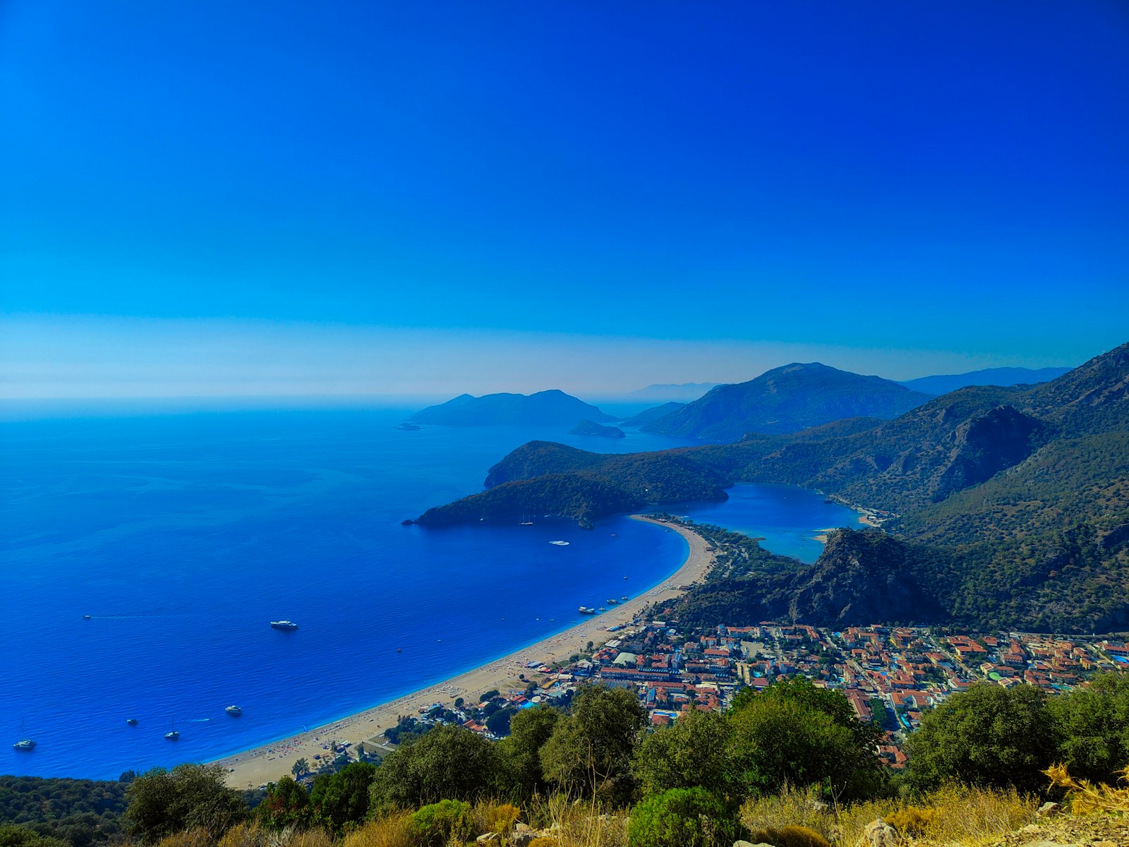 The turquoise lagoon and beach at Ölüdeniz below pine-covered mountains