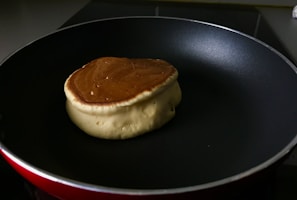 Pouring smooth pancake batter onto a hot buttered skillet