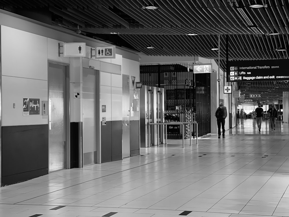 a black and white photo of people walking down a hallway