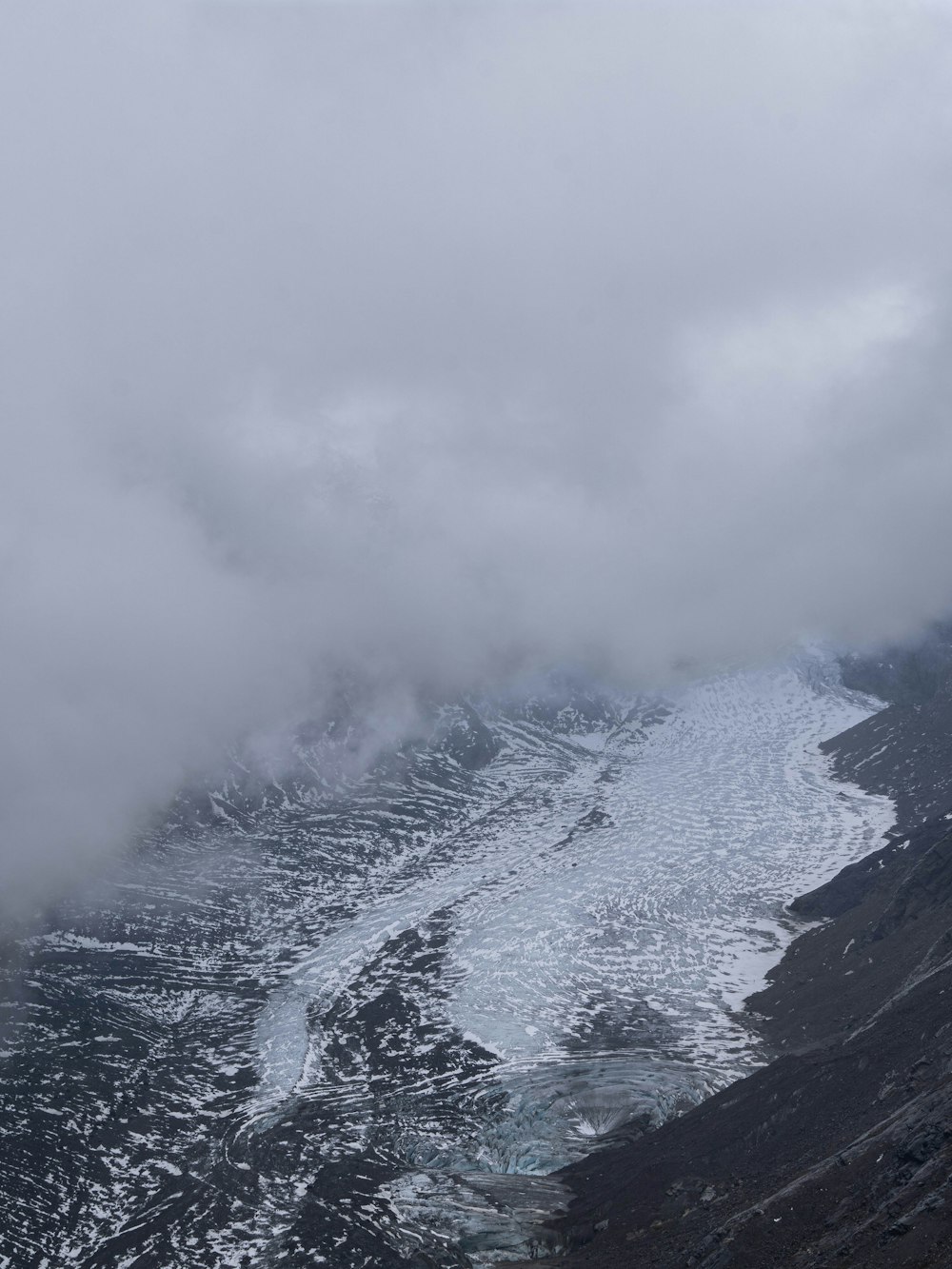 a view of a mountain covered in snow and clouds