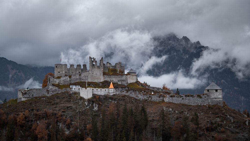 a castle sitting on top of a mountain under a cloudy sky