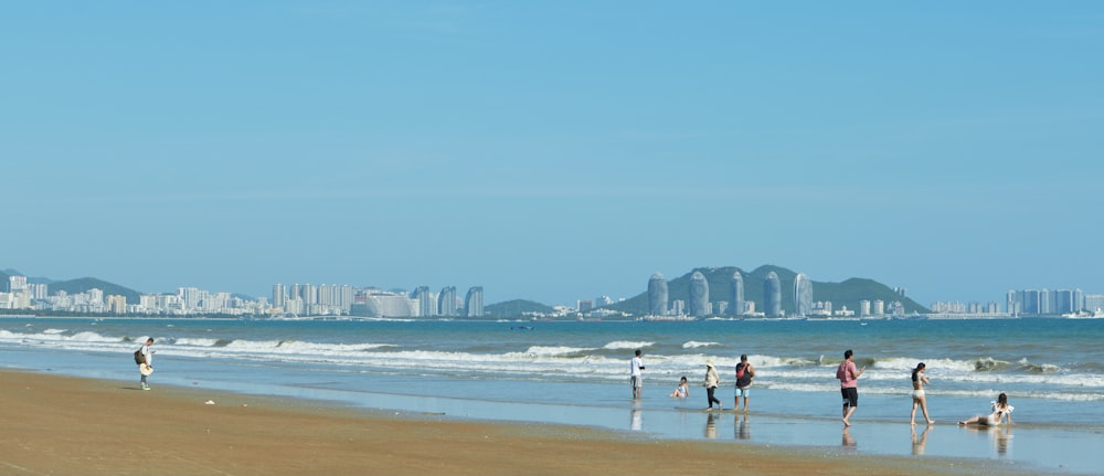 a group of people standing on top of a beach next to the ocean