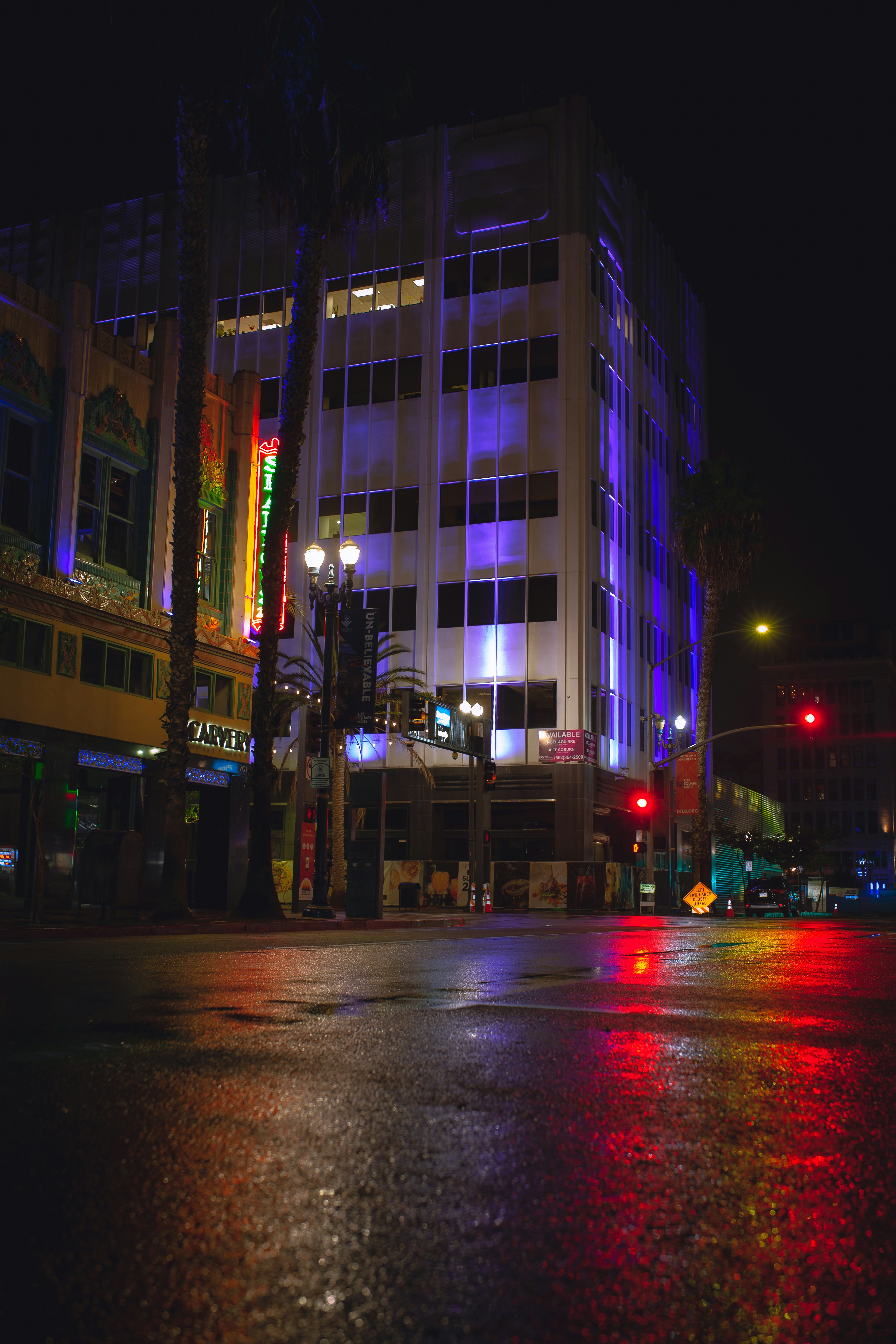 Glowing neon city streets reflected in wet pavement at night with purple and cyan lights