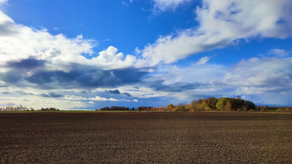 a plowed field under a cloudy blue sky