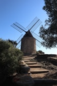 a windmill sitting on top of a hill next to trees