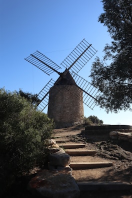a windmill sitting on top of a hill next to trees
