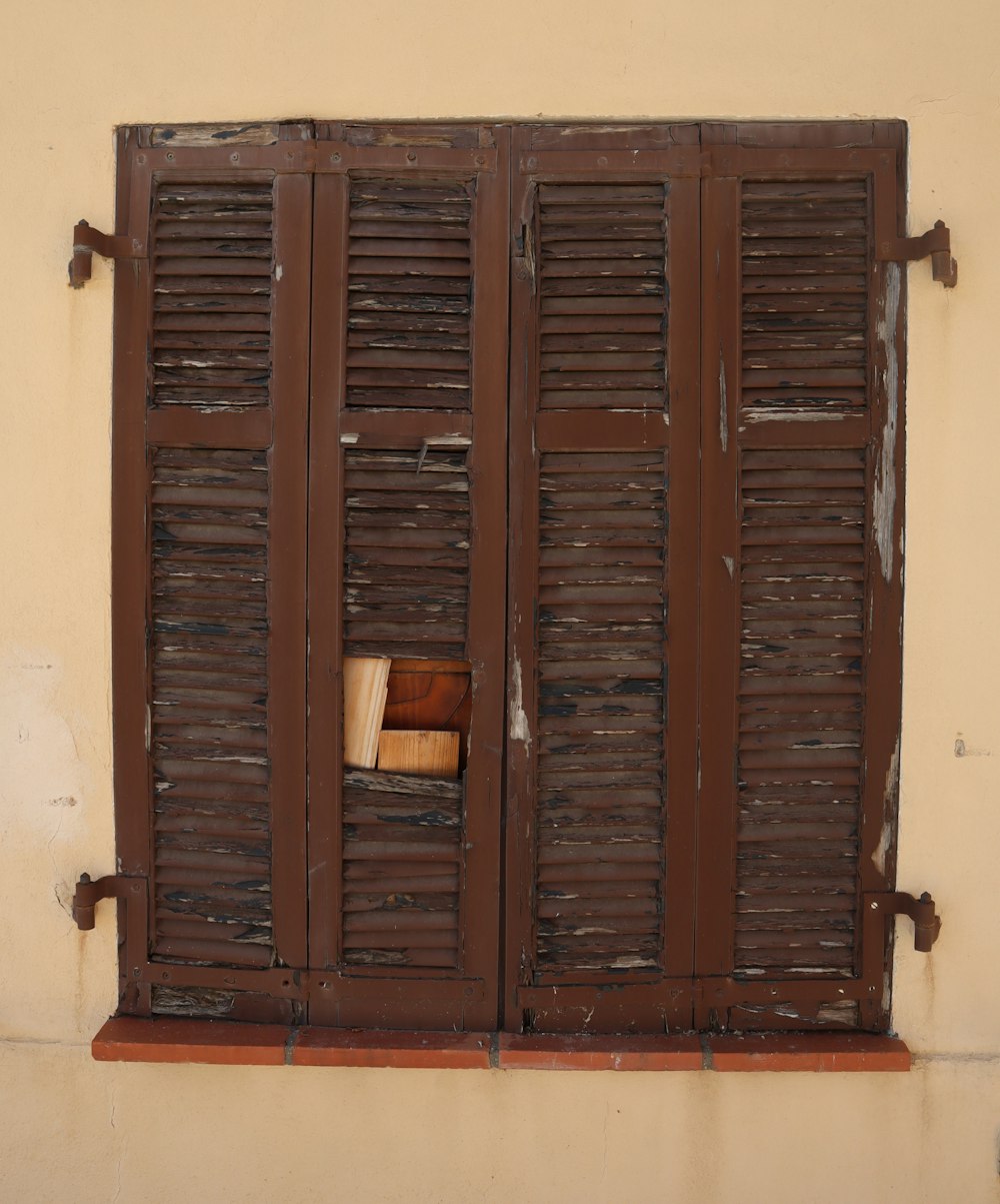 uma janela aberta com persianas de madeira em uma parede