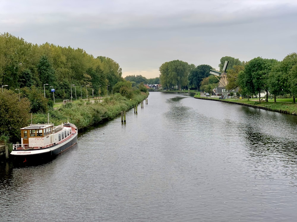 a boat traveling down a river next to a lush green forest