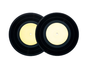 Two black vinyl records with light yellow labels placed side by side against a white background.
