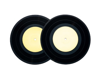 Two black vinyl records with light yellow labels placed side by side against a white background.