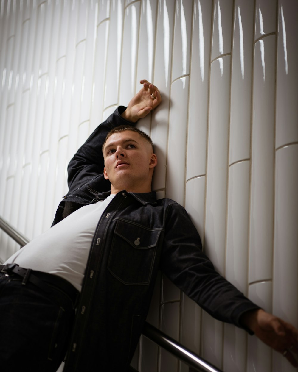 a man leaning against a wall with his hand on the wall