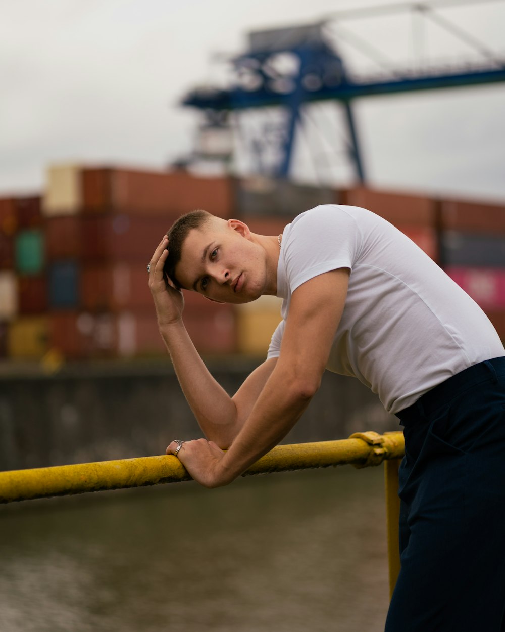 a man leaning on a rail next to a body of water