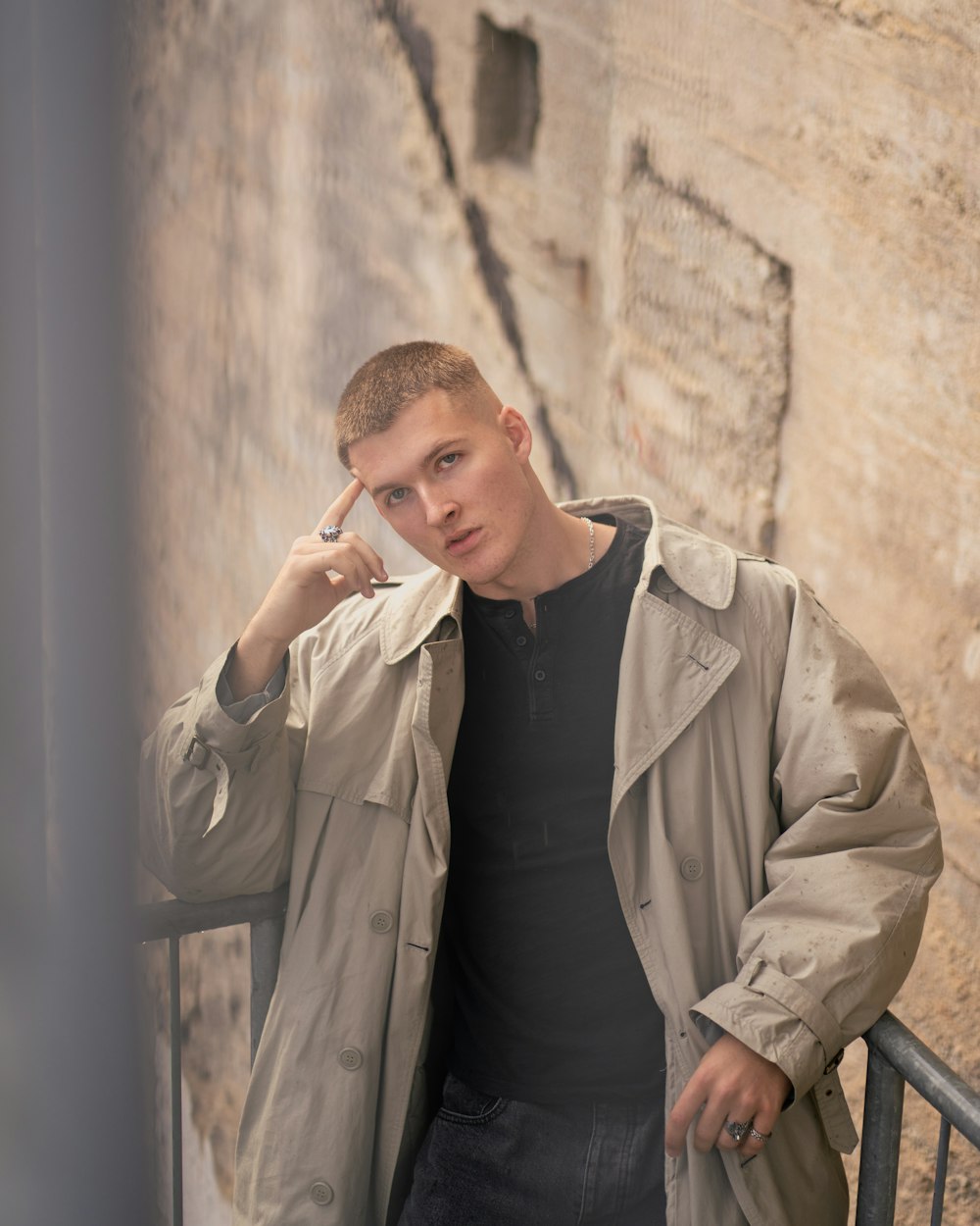 a man leaning against a wall talking on a cell phone