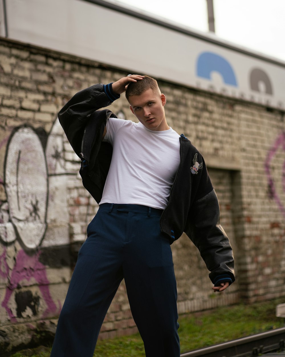 a man standing in front of a brick wall