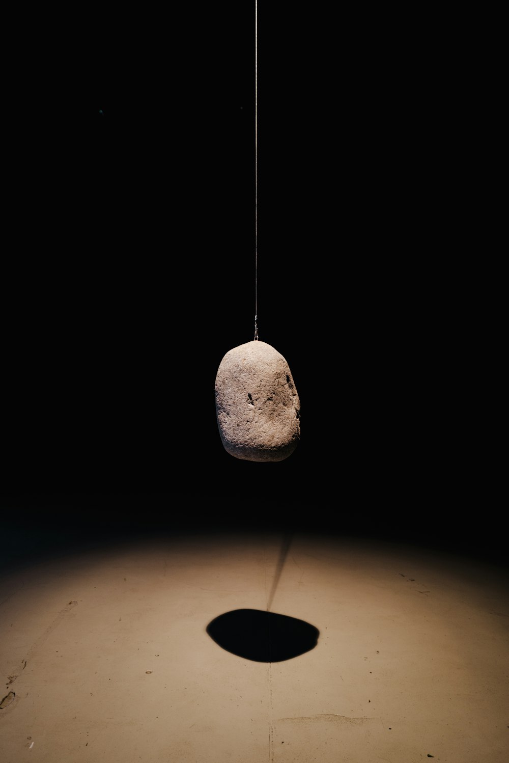 a rock hanging from a string in a dark room