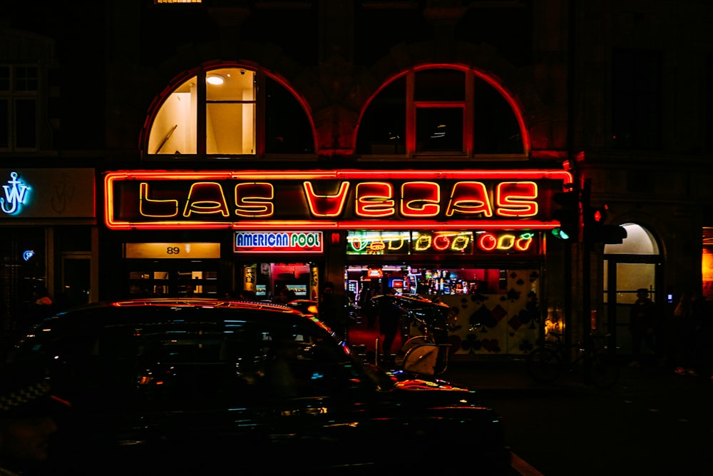 a car parked in front of a building with a neon sign