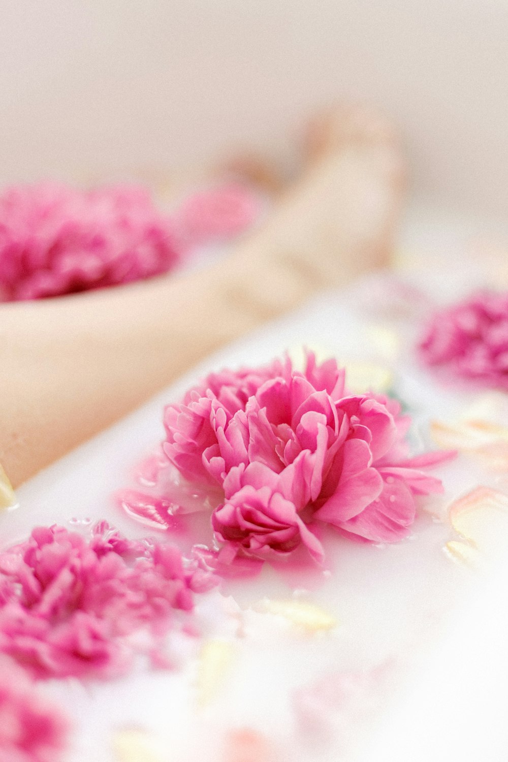 uma pessoa deitada em uma banheira com flores cor-de-rosa