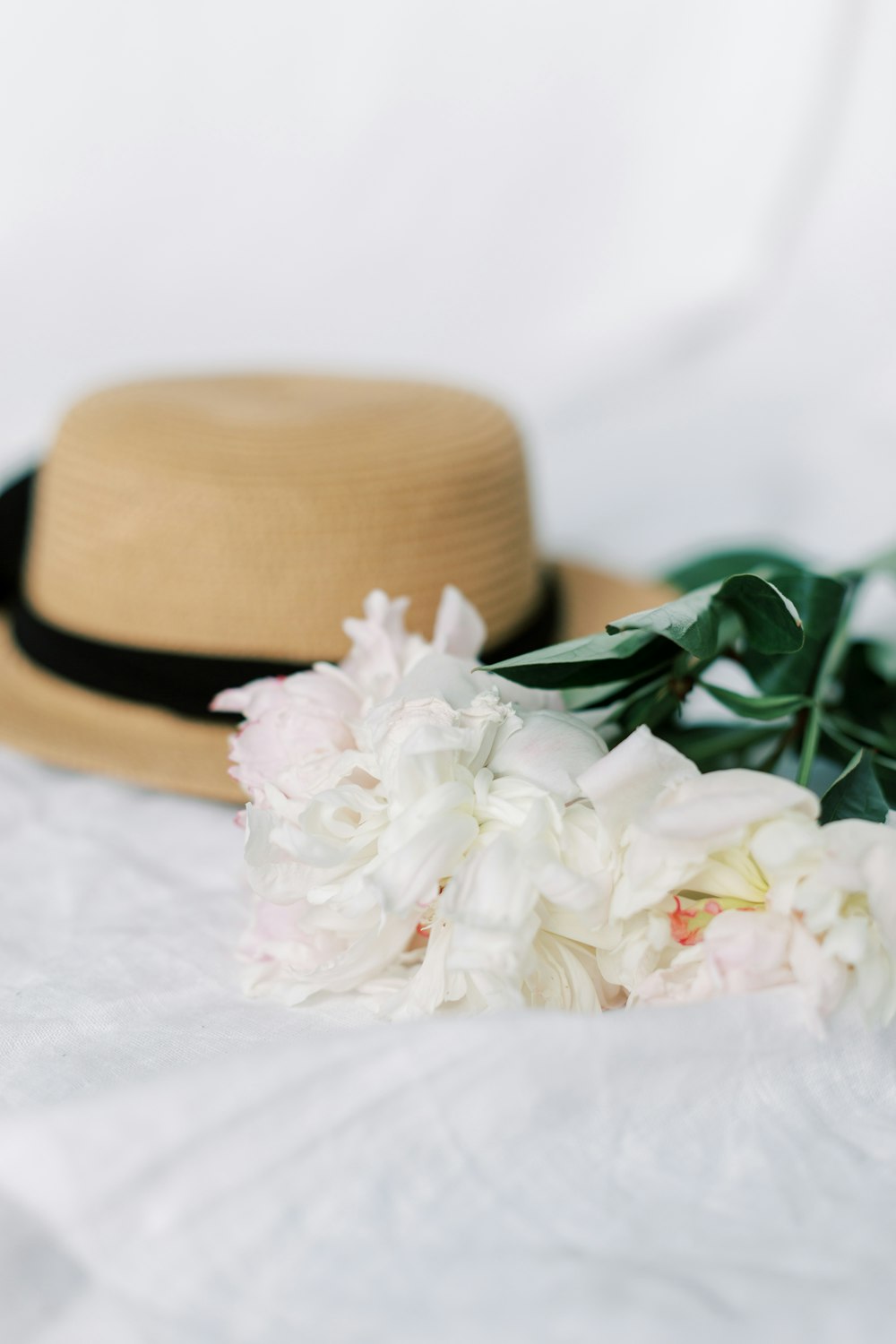 a hat and flowers on a white sheet