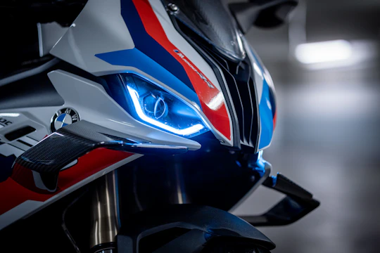 Close-up of a motorcycle headlight glowing bright blue LED lights at dusk.
