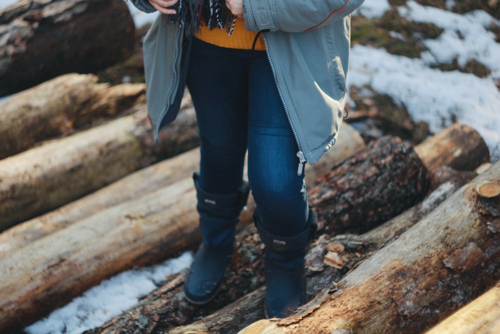 a woman standing on top of a pile of logs