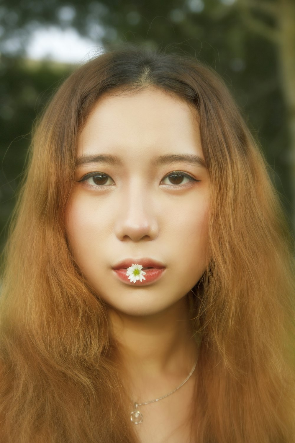 a woman with long hair and a flower in her mouth