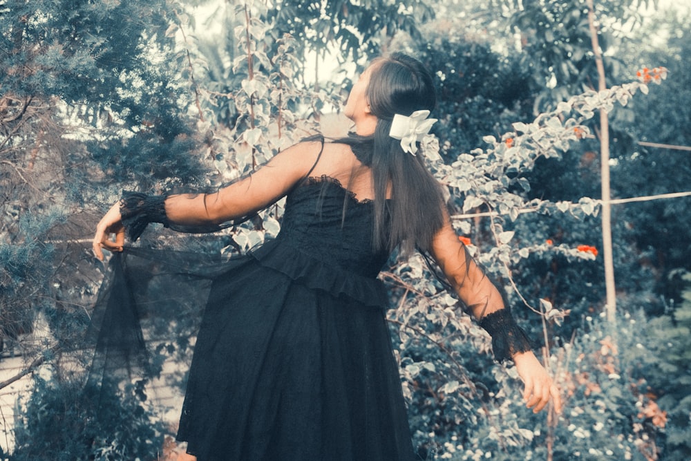 a woman in a black dress standing in a garden