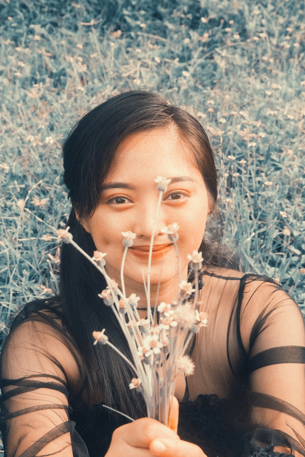 a woman holding a bunch of flowers in front of her face