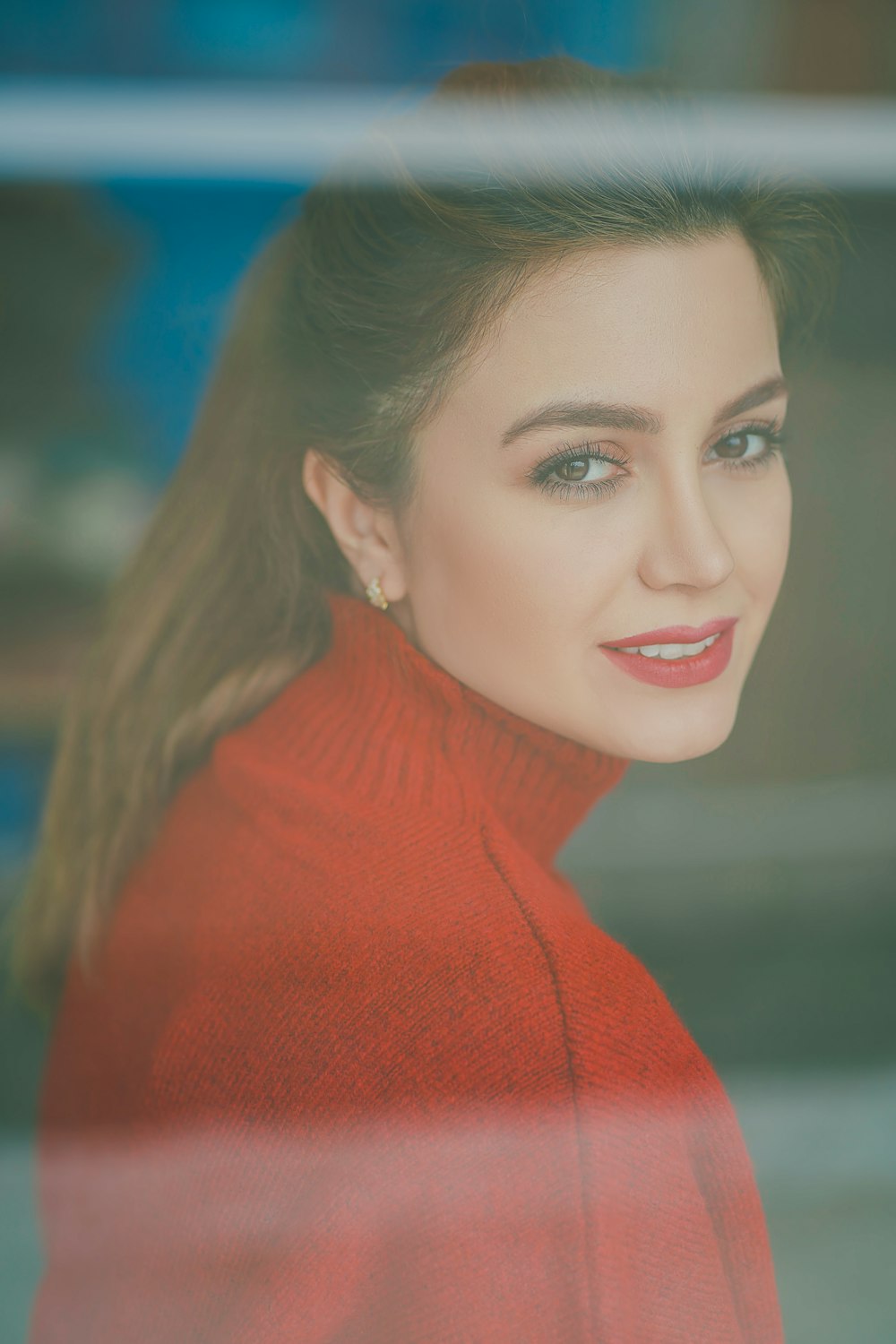 a woman in a red sweater looking out a window