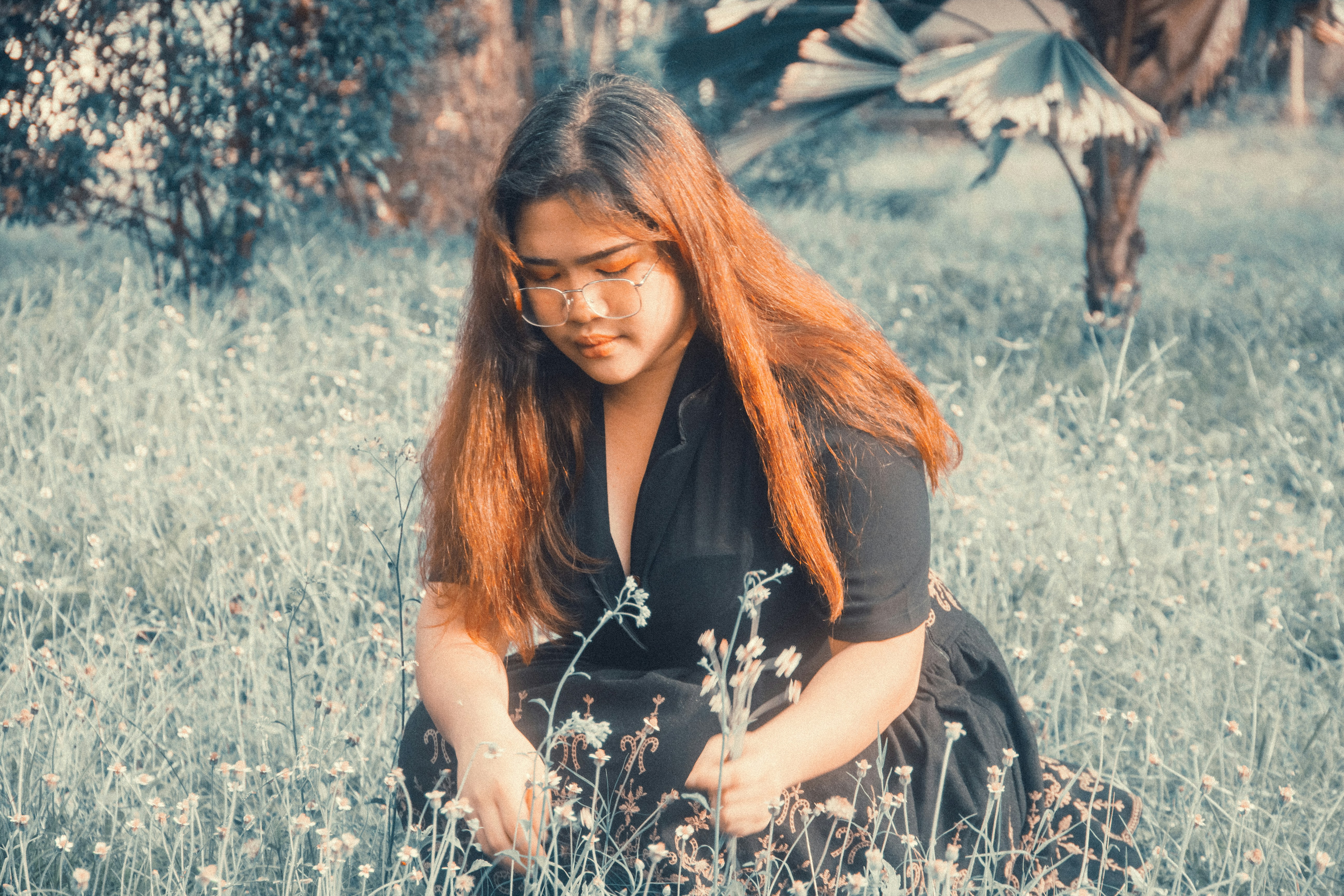 A woman sitting in a field of tall grass photo – Free Woman Image on ...