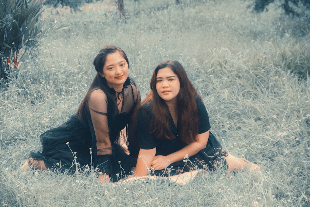 two women sitting in a field of tall grass