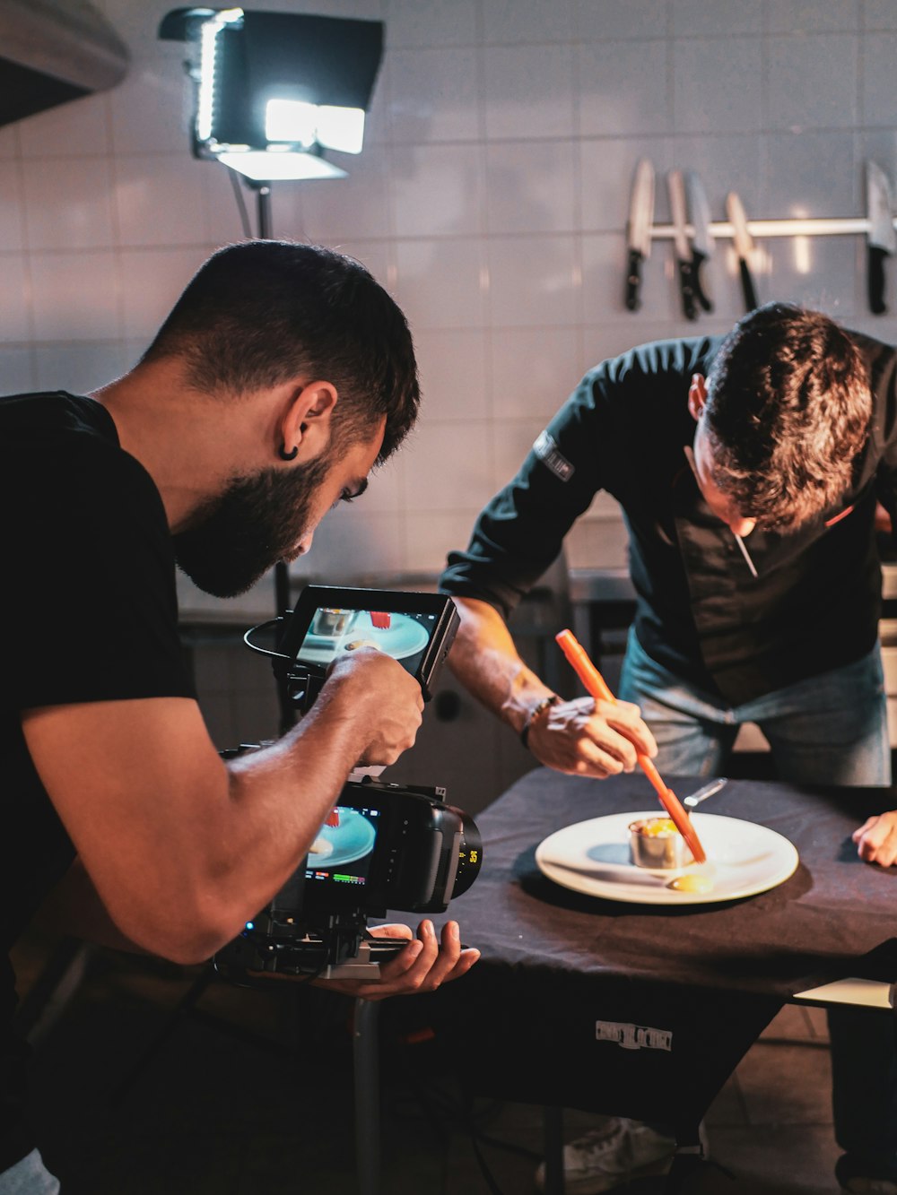 two men in a kitchen preparing food on a plate