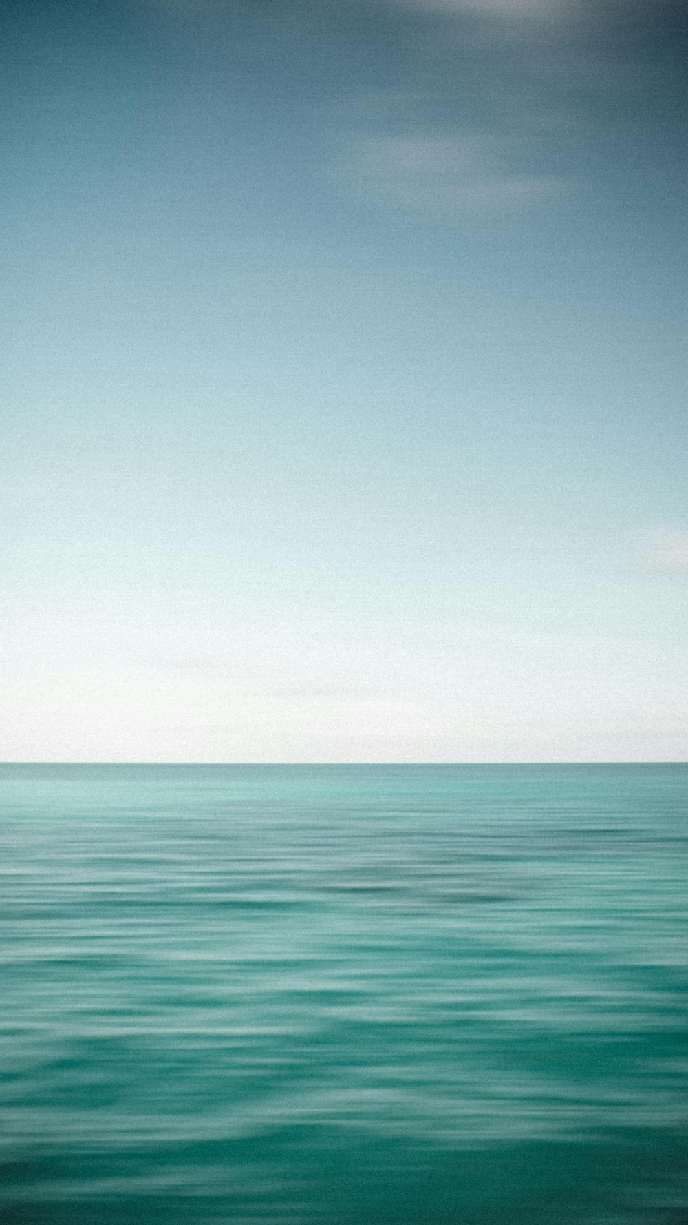 a large body of water sitting under a blue sky