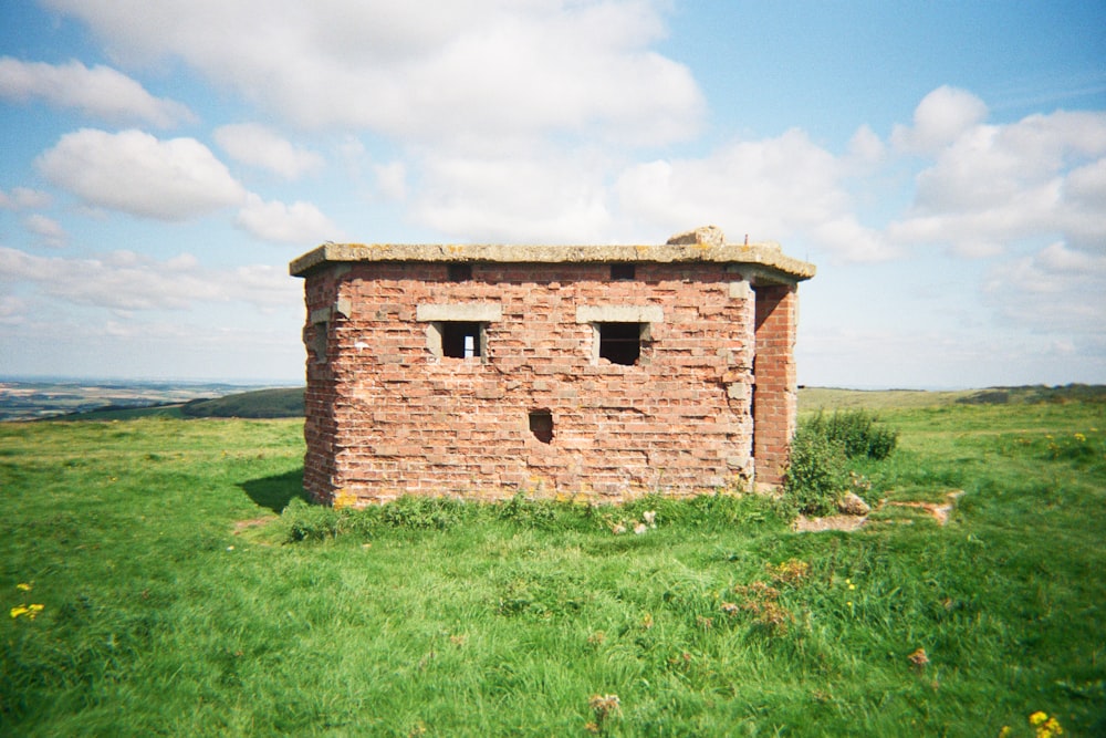 an old brick building in a grassy field