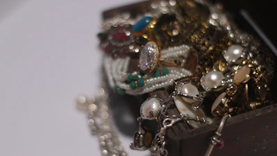 A close-up of a sparkling treasure chest overflowing with colorful gemstone jewelry.
