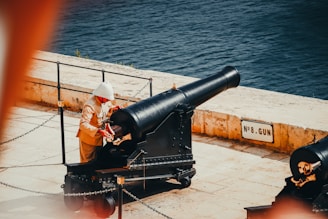 a man sitting on a bench next to a cannon