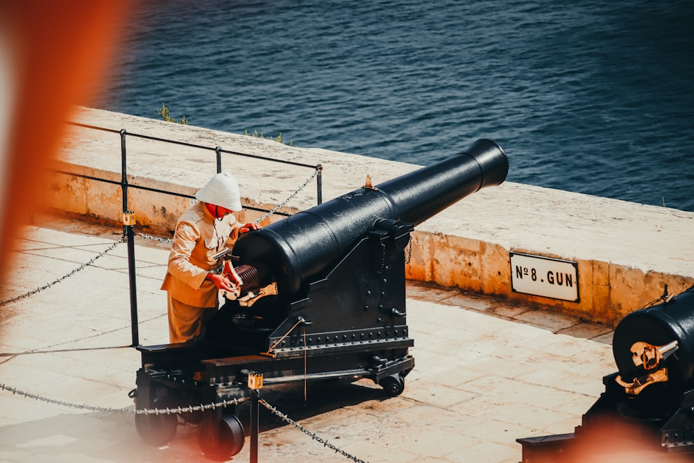 a man sitting on a bench next to a cannon