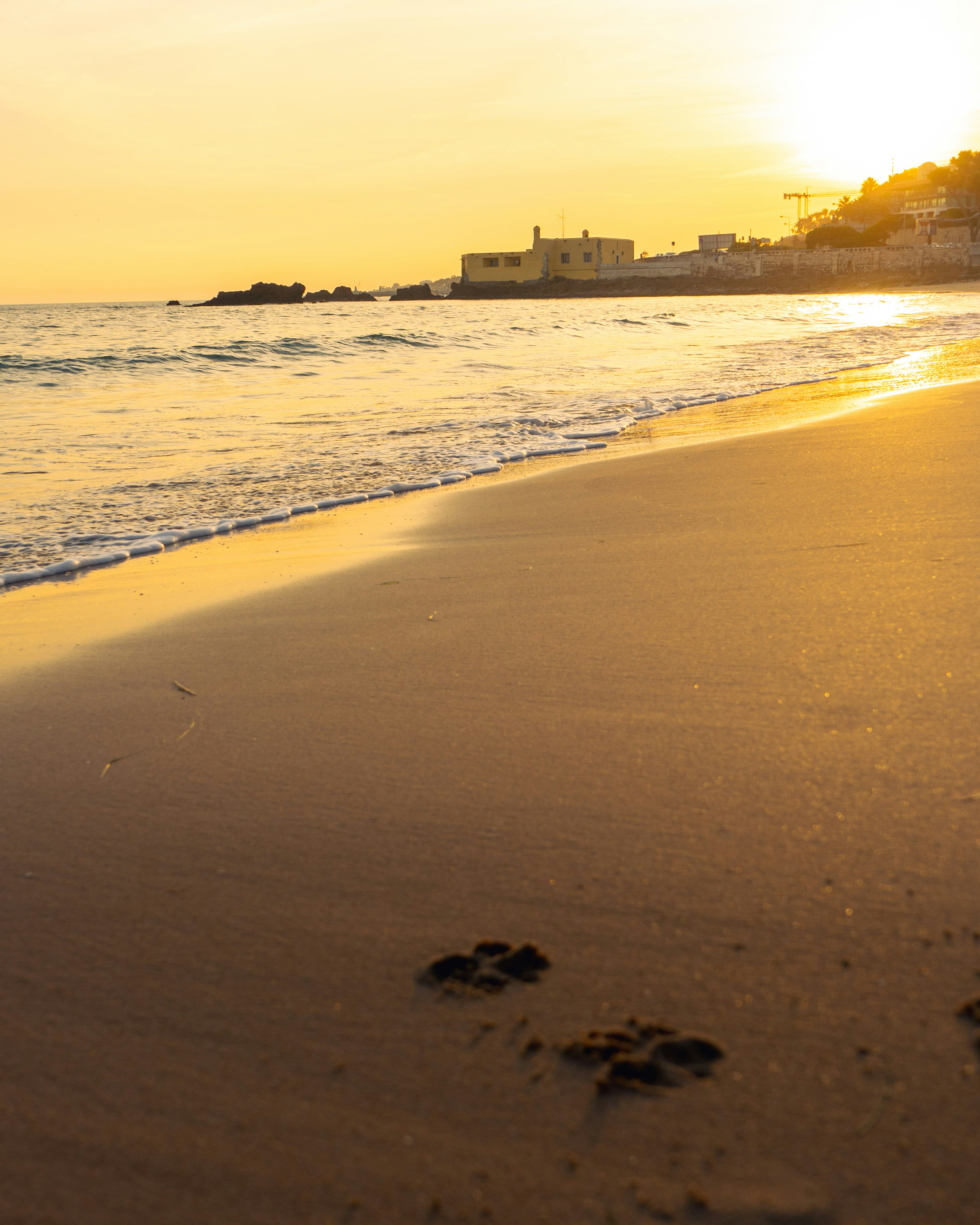 Gouden zonsondergang over een rustig mediterraan strand met warm glanzend zand en zachte golven