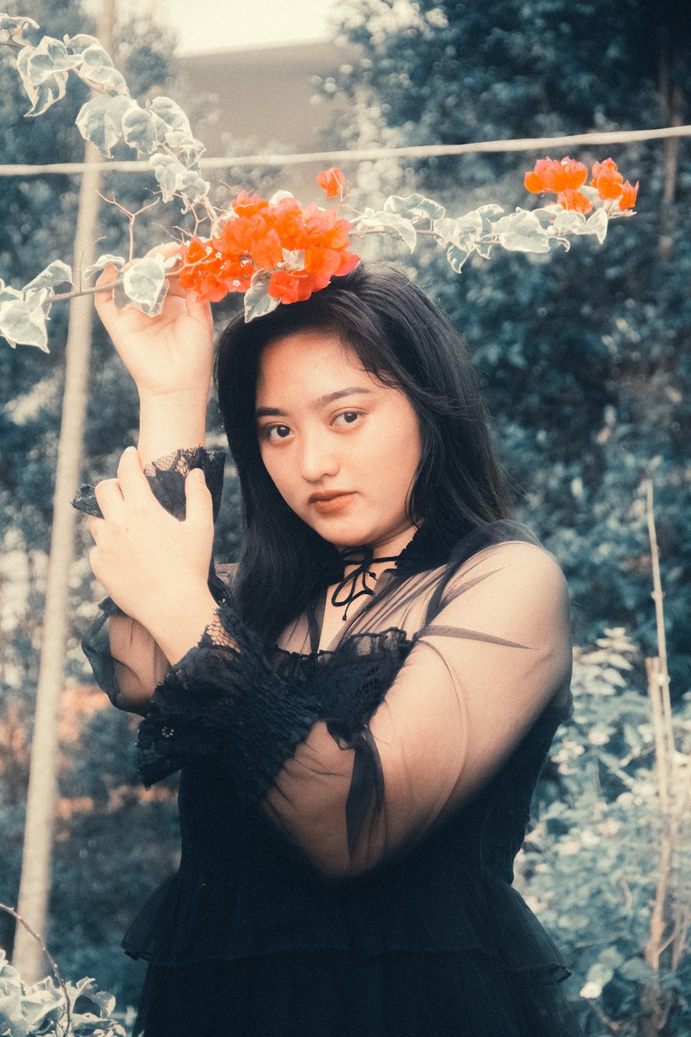 a woman in a black dress holding an orange flower