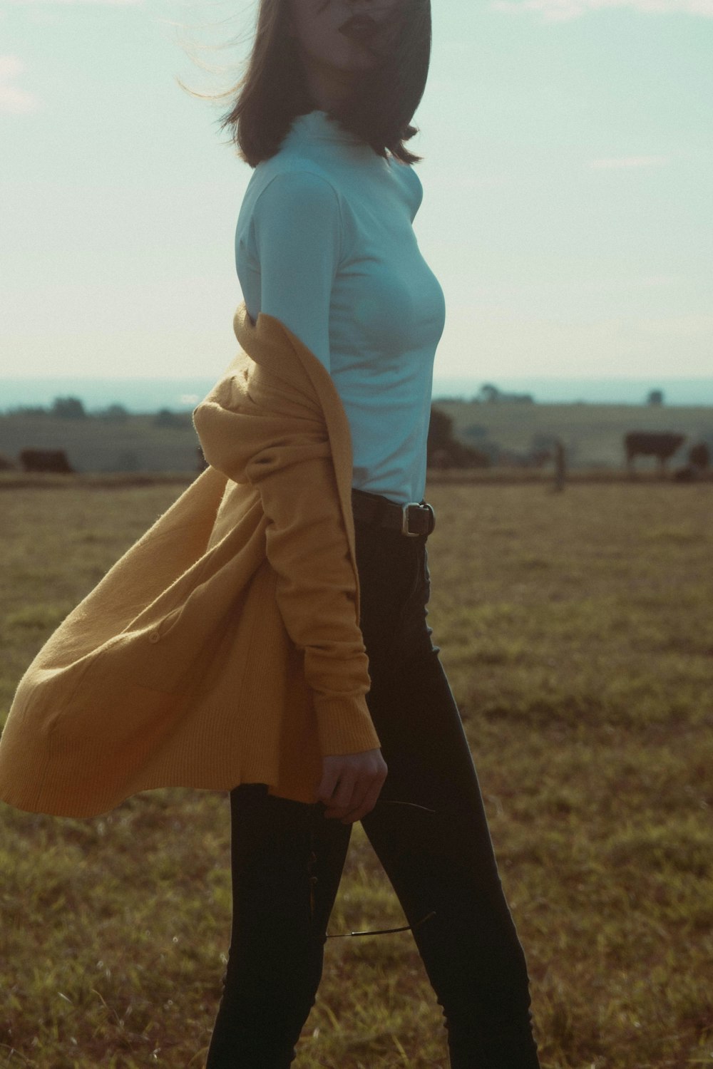 a woman standing in a field with a coat over her shoulders