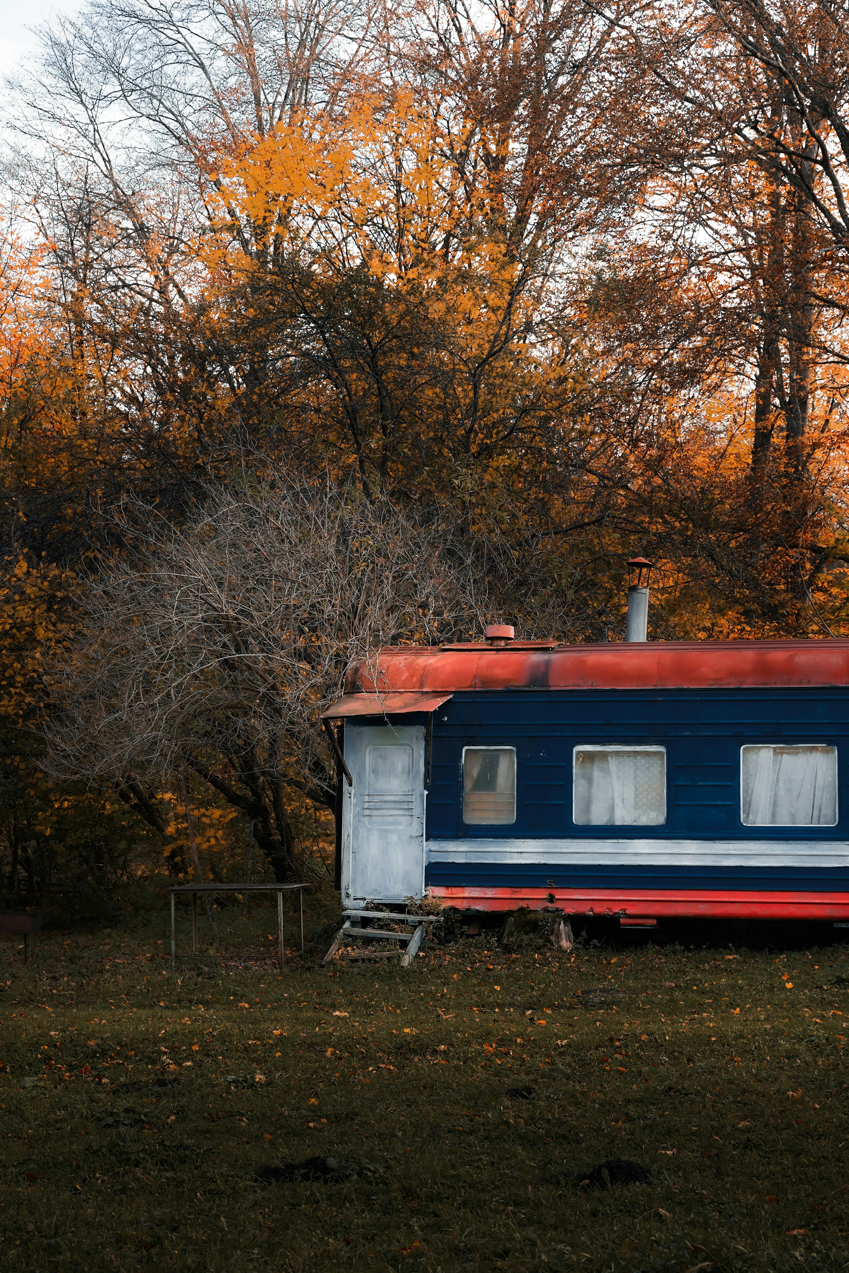 Una casa azul y roja sentada en la cima de un exuberante campo verde