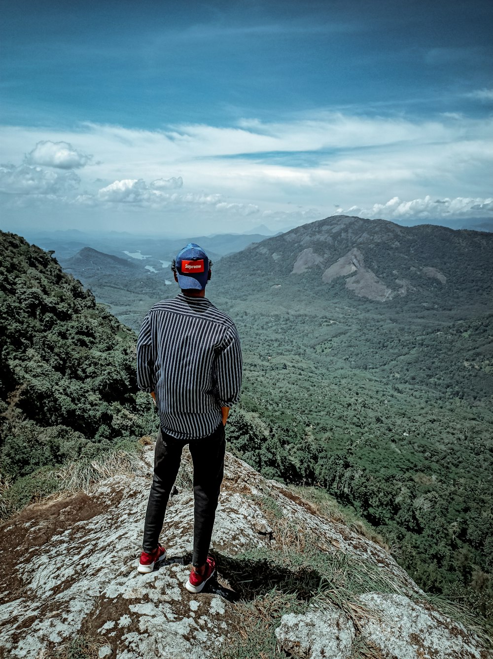 a man standing on top of a lush green hillside