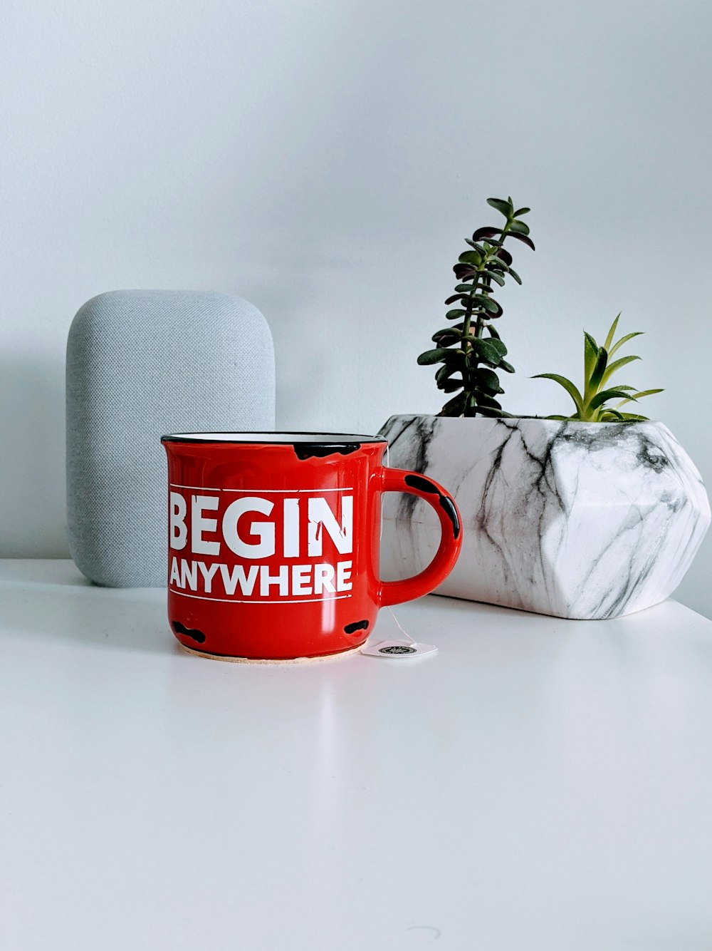 a red coffee mug sitting next to a plant