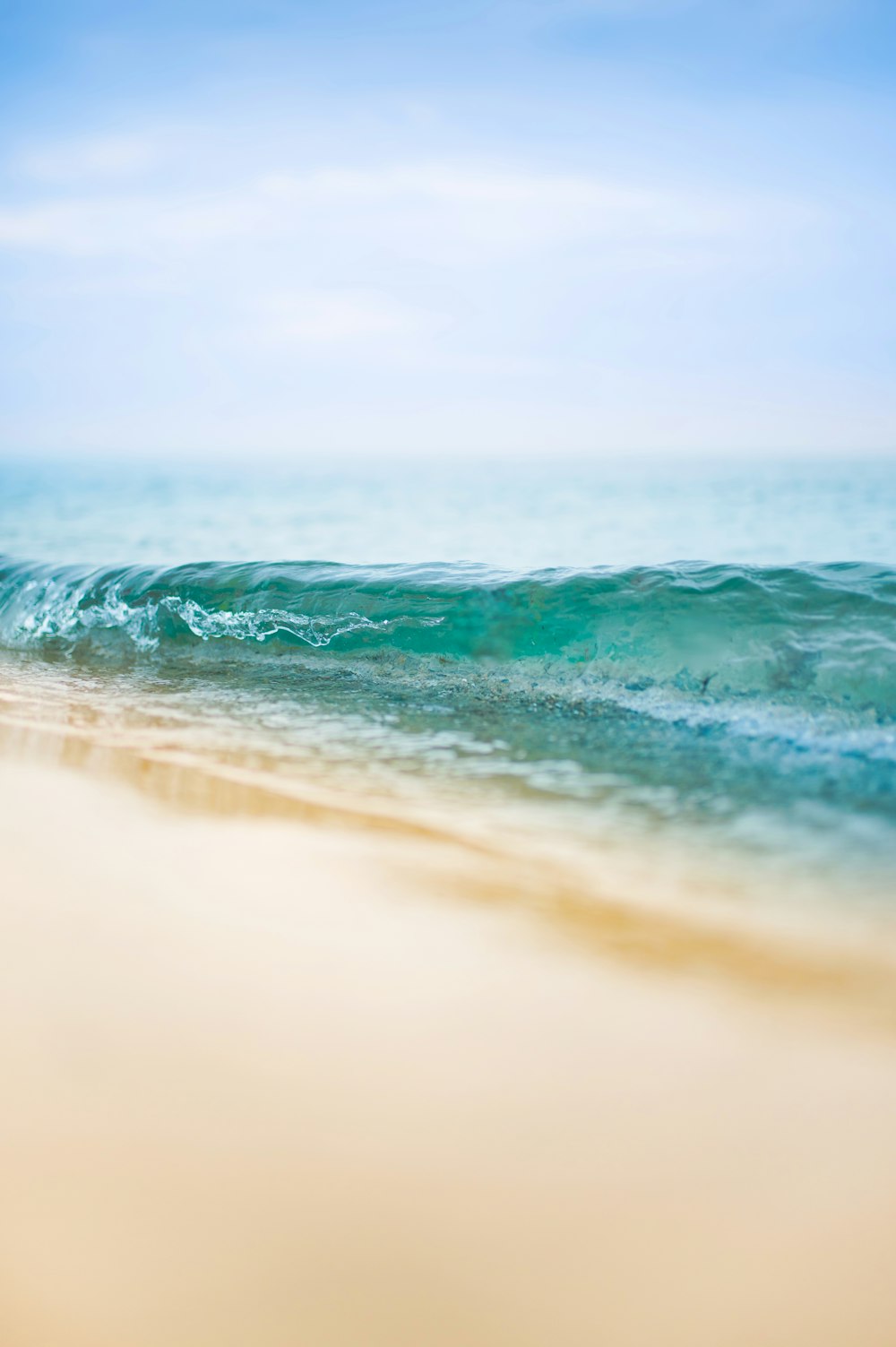 Una foto sfocata di una spiaggia con un'onda in arrivo