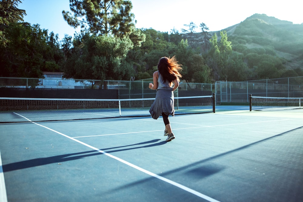 a woman running across a tennis court holding a racquet